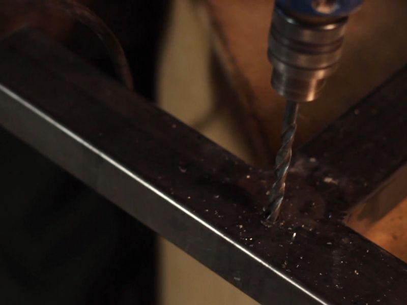 čovek buši rupu u metalnom nameštaju